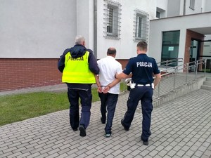 policjanci prowadzą zatrzymanego mężczyznę