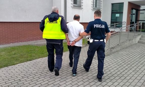 policjanci prowadzą zatrzymanego mężczyznę