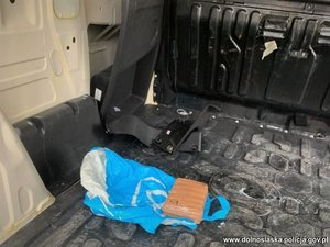 leżąca na pace samochodu paczka oklejona taśmą klejącą na czarnej powierzchni