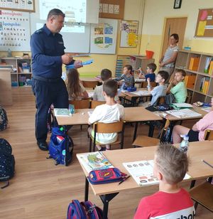 Policjant rozdaje odblaski grupie dzieci.