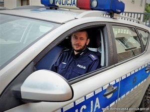 policjant siedzi za kierownica radiowozu policyjnego