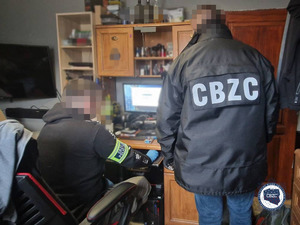 dwaj policjanci podczas przeszukiwania zawartości komputera