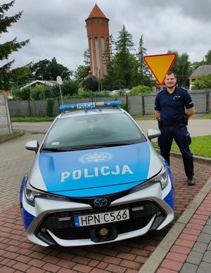 Policjant stoi przy radiowozie policyjnym