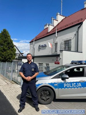 umundurowany policjant stoi przy radiowozie