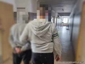 policjant prowadzi zatrzymanego mężczyznę