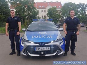 Dwaj policjanci stojący przy radiowozie