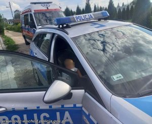 2 latek w policyjnym radiowozie z policjantami, w tle karetka pogotowia