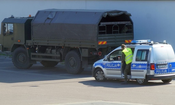 radiowóz policyjny stoi obok ciężarówki wojskowej