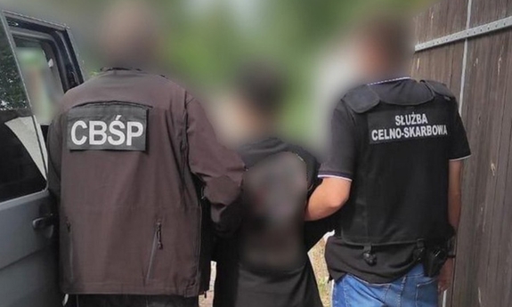 dwaj policjanci z zatrzymanym mężczyzną zakutym w kajdanki