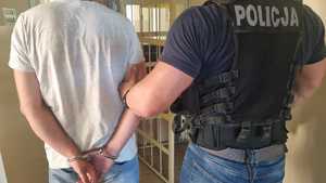 Policjant z zatrzymanym mężczyzną zakutym w kajdanki
