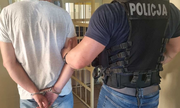 Policjant z zatrzymanym mężczyzną zakutym w kajdanki