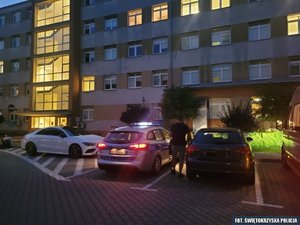 radiowóz i dwa inne samochody na parkingu przed budynkiem