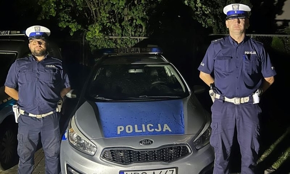 dwaj policjanci stoją przy radiowozie policyjnym
