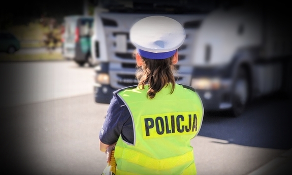 umundurowana policjantka w kamizelce odblaskowej, w tle samochód ciężarowy stoi na poboczu drogi