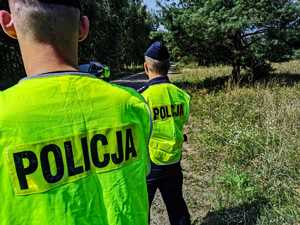 dwaj policjanci stoją na poboczu drogi