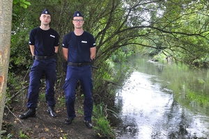 Dwaj policjanci stojący na brzegu rzeki.