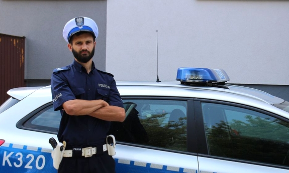 policjant stoi przy radiowozie