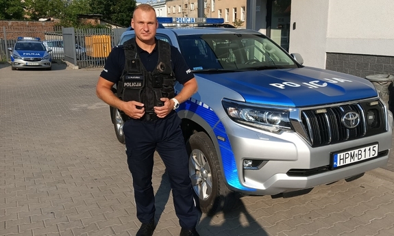 umundurowany policjant stoi przy radiowozie