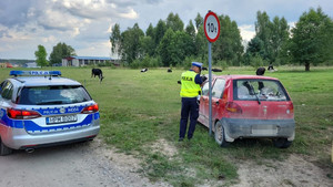 policjanci stoją obok samochodu, obok stoi radiowóz