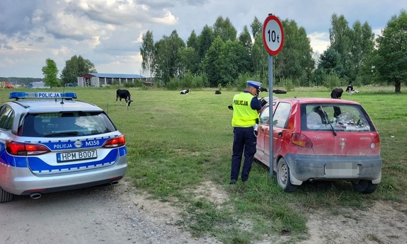 policjanci stoją obok samochodu, obok stoi radiowóz