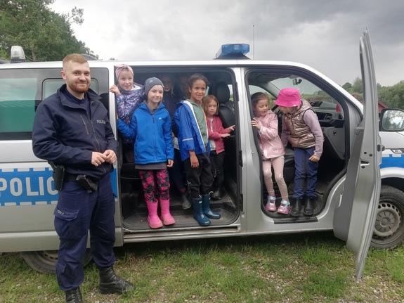 policjanci pozują z dziećmi na tle radiowozu