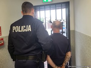 Policjant prowadzi zatrzymanego mężczyznę