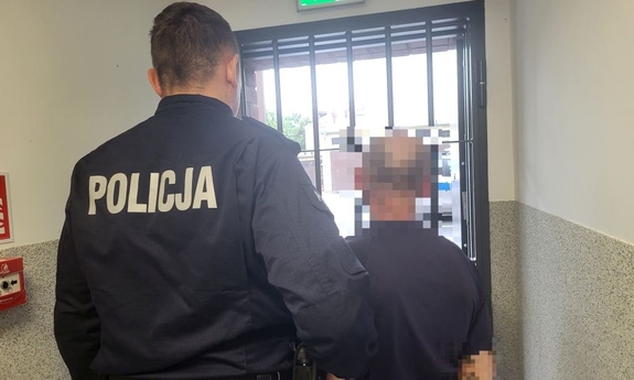 Policjant prowadzi zatrzymanego mężczyznę