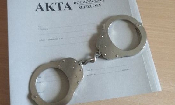 szara teczka na policyjne akta i leżące na nich kajdanki
