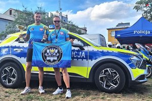 policjanci w strojach sportowych z pucharami, w tle oznakowany radiowóz