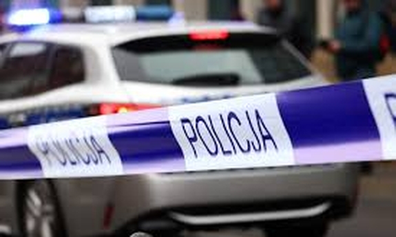 na pierwszym planie taśma policyjna z napisem Policja, w tle radiowóz policyjny
