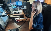policjantka na stanowisku dowodzenie komendy policji w czasie służby, siedzi przy biurku przed komputerem, rozmawia przez telefon