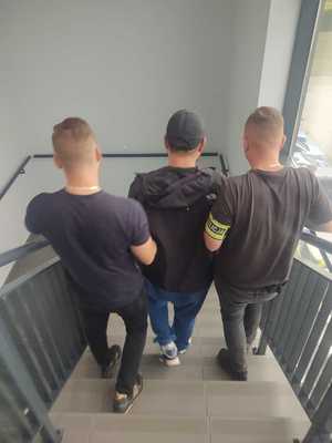 policjanci prowadzą zatrzymanego po schodach