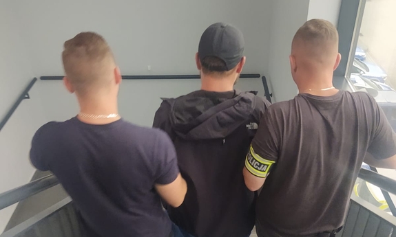 policjanci prowadzą zatrzymanego po schodach