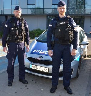 umundurowani policjanci stoją przy radiowozie