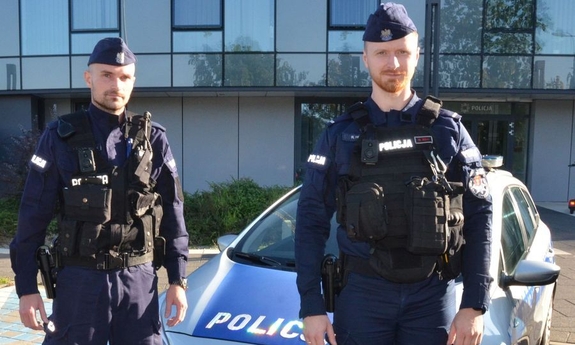 umundurowani policjanci stoją przy radiowozie