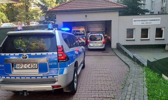 Oznakowany radiowóz stoi przed budynkiem Instytutu Gruźlicy i Chorób Płuc