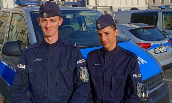 umundurowany policjant i policjantka, w tle stoi radiowóz
