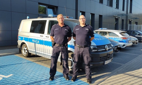 umundurowani policjanci stoją przy radiowozie