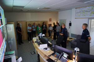 Grupa ludzi wraz z policjantami w pomieszczeniu służbowym KWP w Bydgoszczy