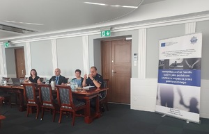 Dwójka kobiet i mężczyzn siedząca przy stole prezydialnym