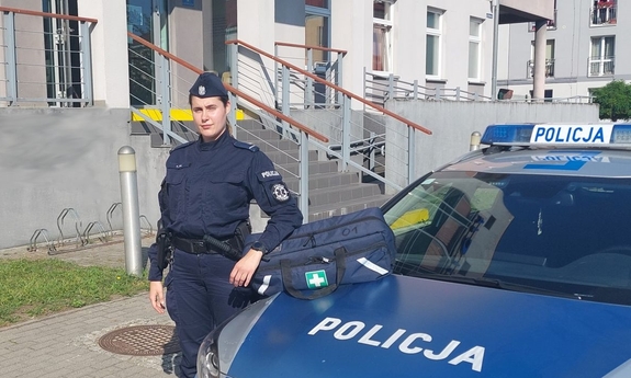 umundurowana policjantka stoi obok radiowozu