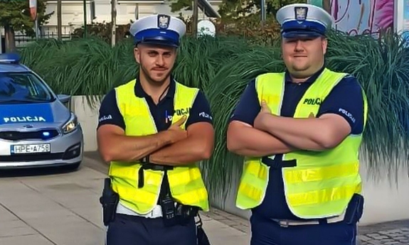 dwóch umundurowanych policjantów w kamizelkach odblaskowych