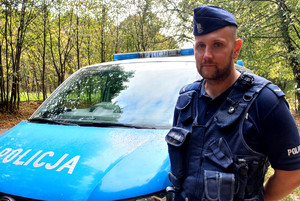 Policjant stoi przy radiowozie