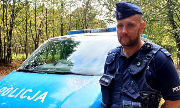 Policjant stoi przy radiowozie