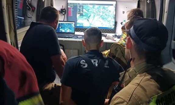 Policjanci i strażacy przeglądają teren poszukiwań