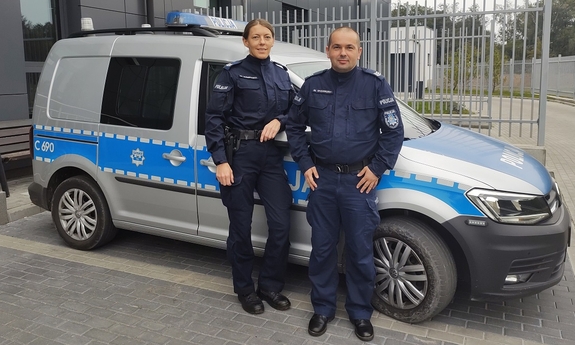 policjant i policjantka przy radiowozie