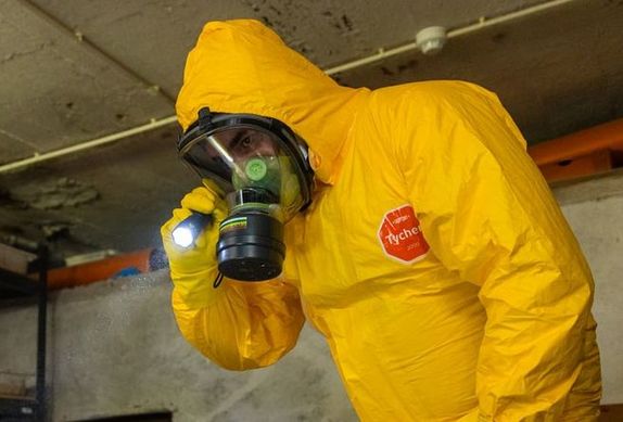 Osoba w żółtym kombinezonie ochronnym z maską gazową na twarzy