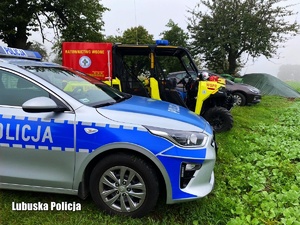 radiowóz policyjny i inne pojazdy służb stoją na skraju pola