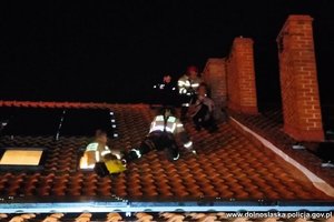 Policjanci i strażacy na dachu pomagają mężczyźnie