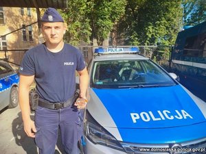 Policjant stoi przy radiowozie